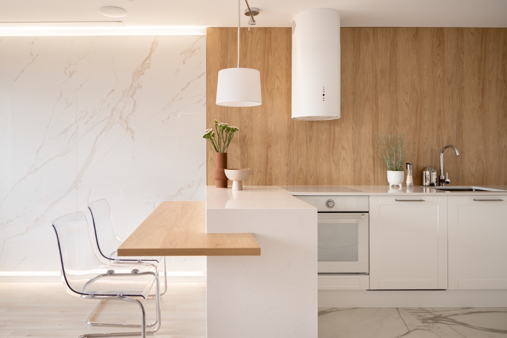 Minimalist White Kitchen with Light Oak Accent Wall Marble Backsplash and Clear Acrylic Chairs.jpg