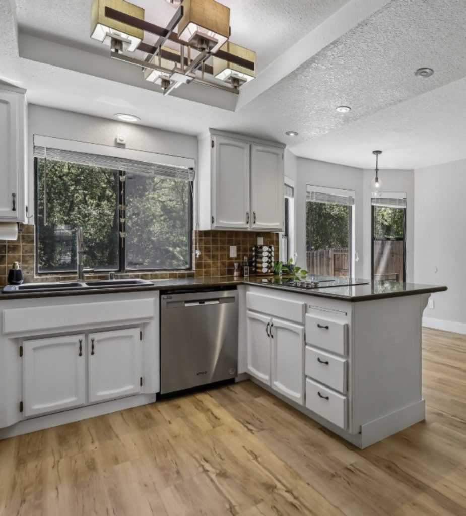 Modern White Kitchen with Granite Countertops Stainless Steel Dishwasher and Geometric Chandelier.jpg