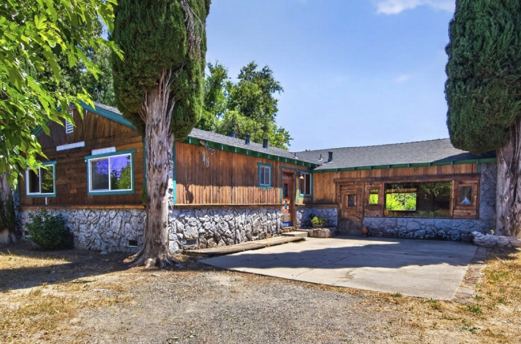 Rustic Wood Siding Mountain Home with Stone Foundation and Flanking Tall Cypress Trees.jpg
